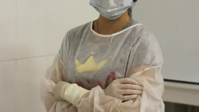Healthcare worker in gown, gloves, mask and cap demonstrating aseptic technique used in CAUTI prevention