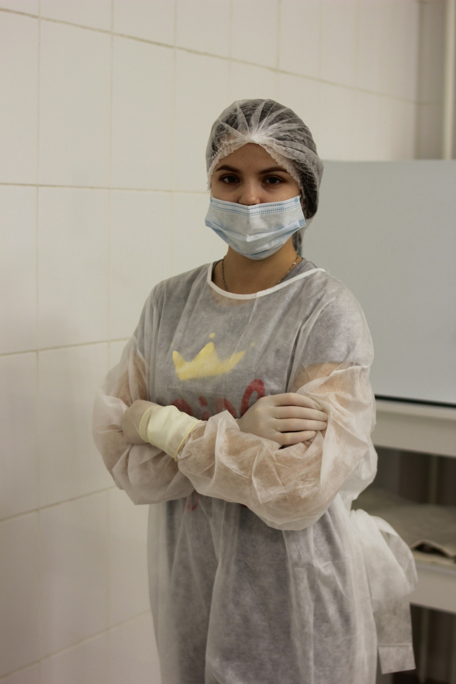 Healthcare worker in gown, gloves, mask and cap demonstrating aseptic technique used in CAUTI prevention