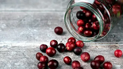 Glass of cranberry juice next to cranberry capsule pills, comparing options for UTI prevention
