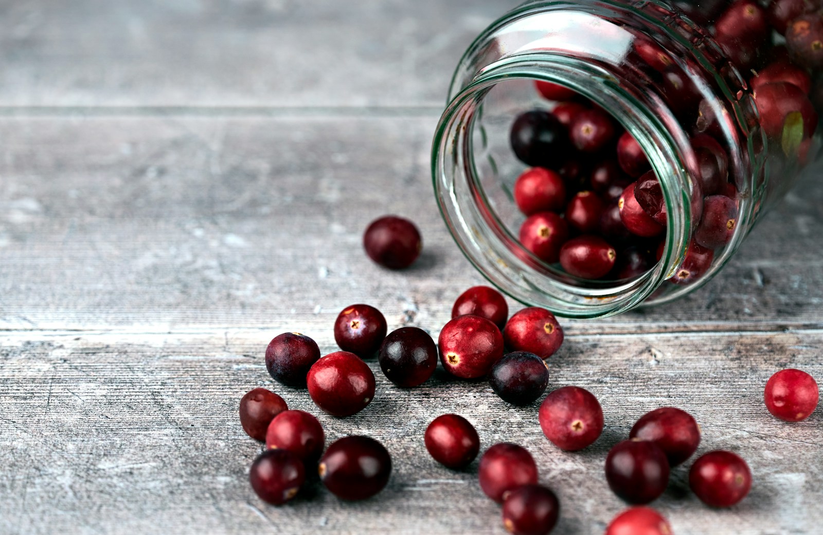 Glass of cranberry juice next to cranberry capsule pills, comparing options for UTI prevention