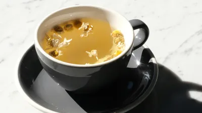 Cup of plain chamomile tea with dried flowers, a low-acid drink that rarely irritates the bladder