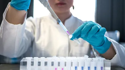 Scientist working with laboratory pipette and test tubes, representing the clinical research behind the MV140 UTI vaccine