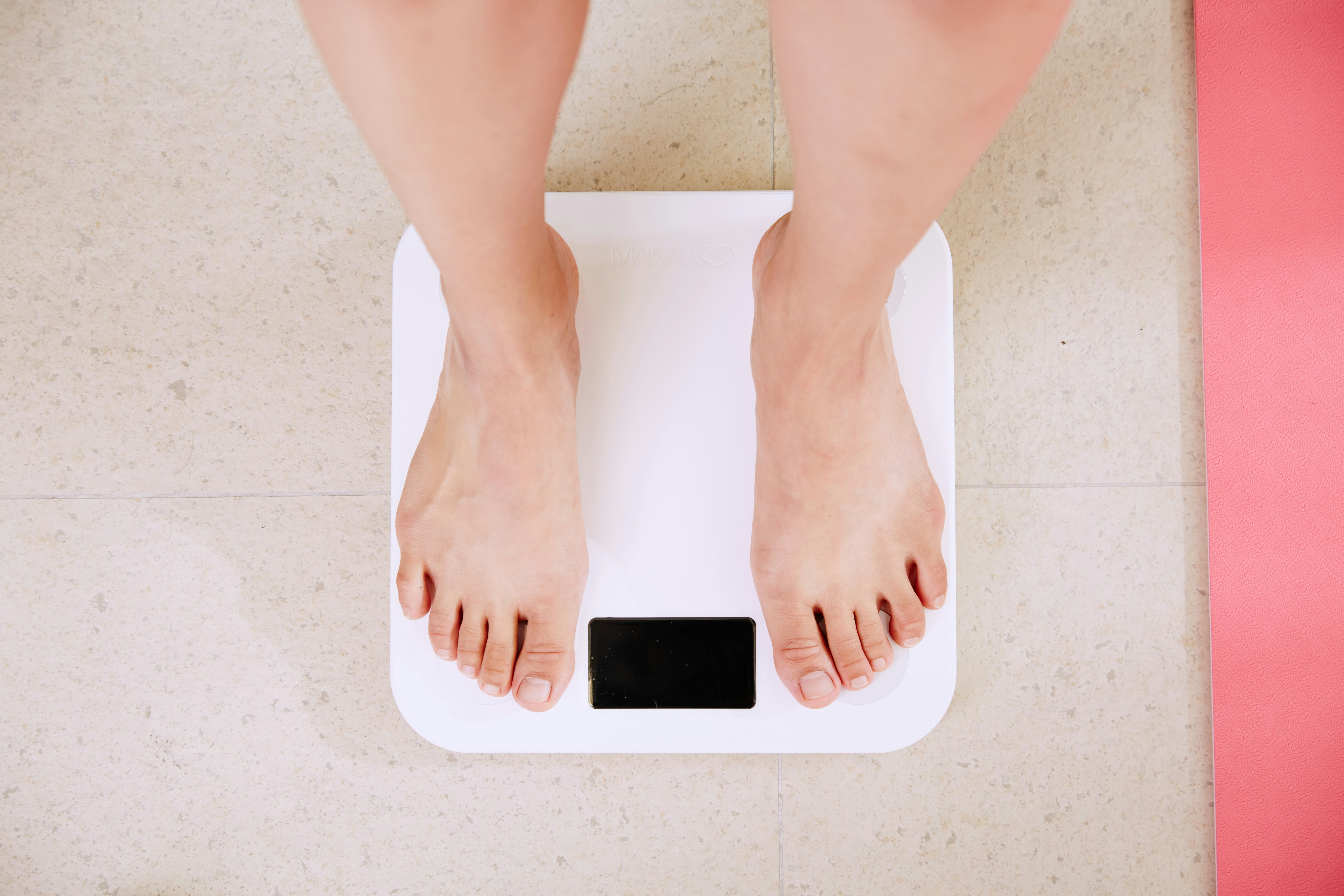Person stepping onto a bathroom scale, representing the connection between obesity and bladder health