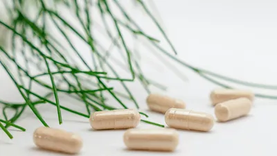 Probiotic capsules and vaginal suppositories beside a microscope slide, illustrating probiotic strains for recurrent UTI prevention