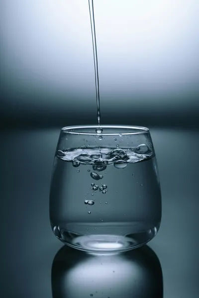 Person holding a glass of water during cancer recovery, representing hydration for radiation cystitis management