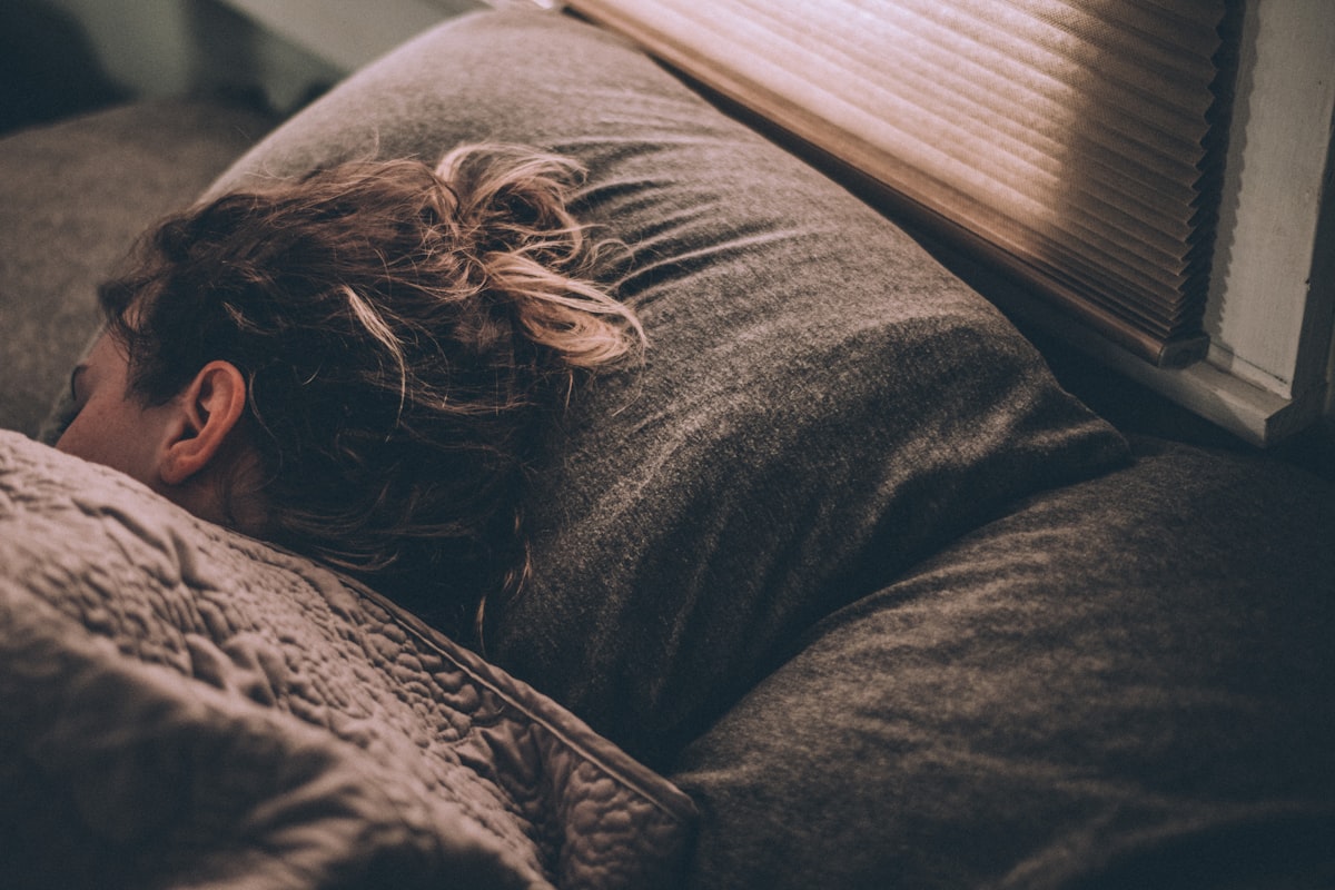 Person sleeping peacefully in a dark, cool bedroom with soft nightlight near the door