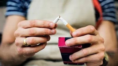 Broken cigarette lying on a table next to a glass of water, representing quitting smoking for bladder health