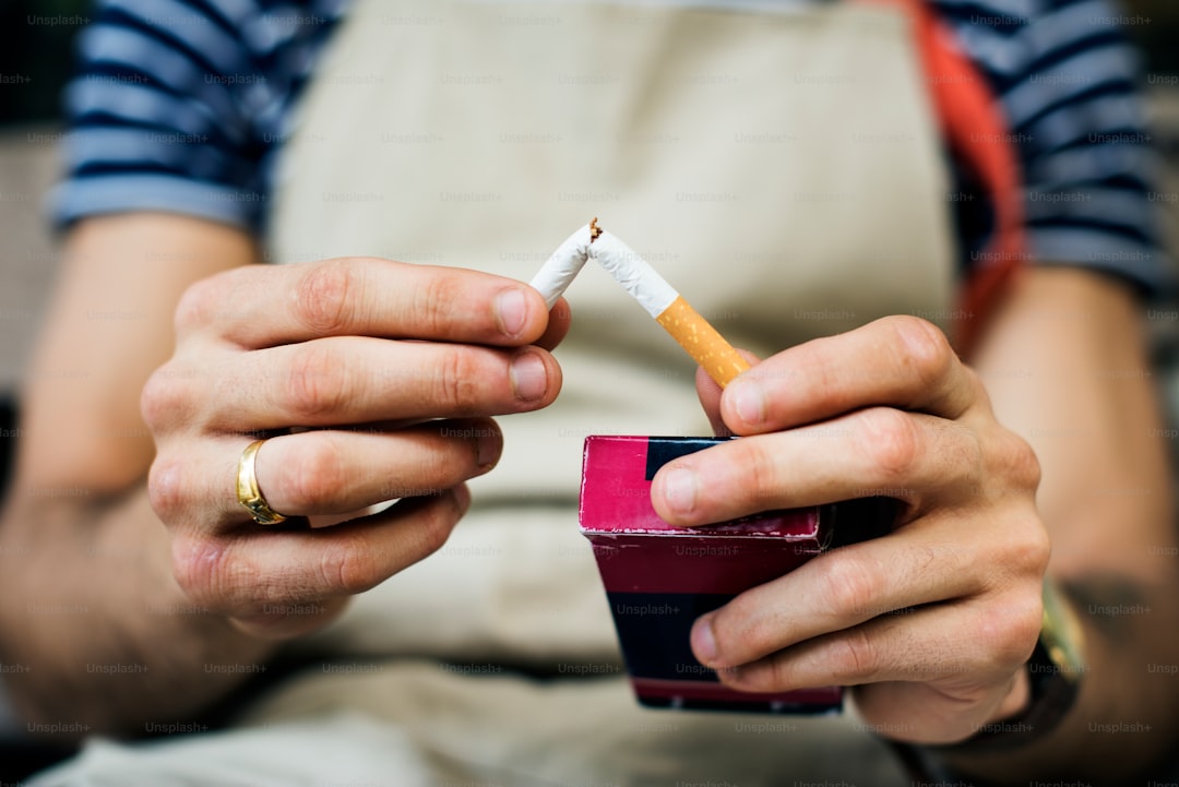 Broken cigarette lying on a table next to a glass of water, representing quitting smoking for bladder health