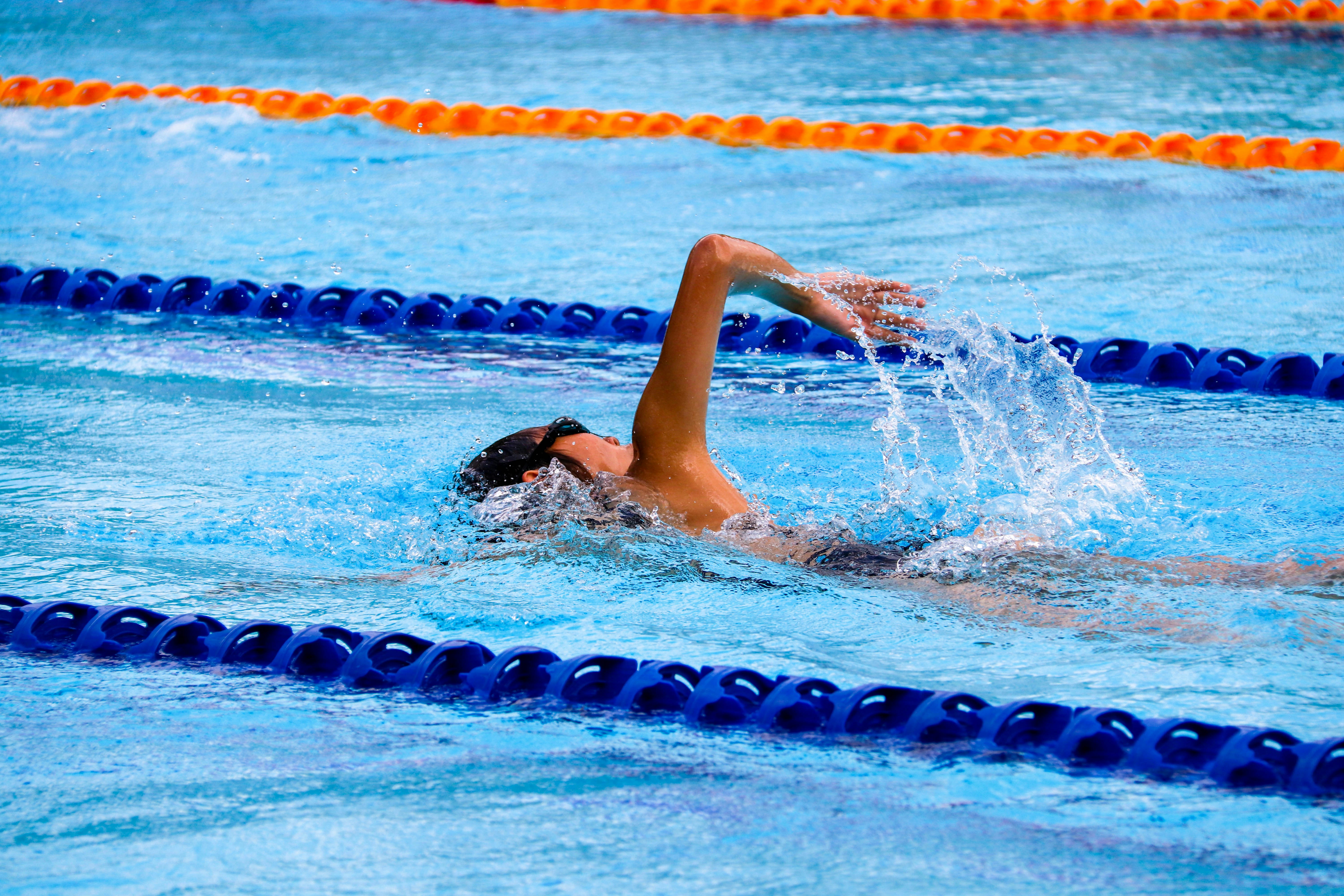 Woman swimming laps in an outdoor pool, staying active for bladder health