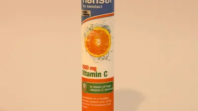 Vitamin C tablet next to a glass of water on a bedside table for evening UTI prevention dosing